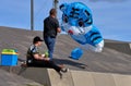 Two men with a big blue kite in shape of a tiger