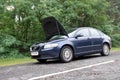 Volvo S40 car with open hood on a country road in the forest