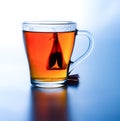 Brewed tea with a bag in a cup. High contrast. Saturated colors. White-blue background. Deep shadow.