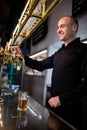 Brewer filling beer in beer glass from beer pump