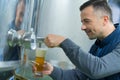 brewer filling glass beer from vat