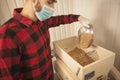 Brewer pouring barley seeds into grain mill at his brewery