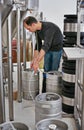 Brewery, man and pipe in tank with manufacturing for craft beer, alcohol and production process in factory. Industrial Royalty Free Stock Photo