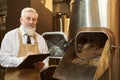 Expert of brewery standing near equipment holding folder.