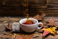 Brewing tea concept. Cup pouring with water or tea with splashes on dark wooden background. Cup, autumn leaves and