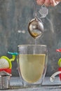 Brews tea in transparent glass with boiling water and tea strainer