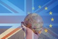 Brexit concept of a hand holding a globe focusing on Europe in a field over layered with the Union Jack and E.U flag. To represent