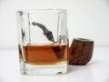 Briar smoking pipe behind a glass of whiskey close side view wit