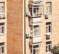 Brick apartment building sunny facade with its plastic glazing of windows and balcomies, air conditioners Royalty Free Stock Photo