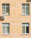 Brick apartment building sunny facade wall with its plastic windows with jalousies, curtains and air conditioner