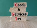 Brick blocks with letters GST -goods and services tax on green background. State financial policy to regulate tax collection rules