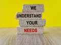 Brick blocks with WE UNDERSTAND YOUR NEEDS text on beautiful yellow background. Client relationship and marketing strategy concept Royalty Free Stock Photo