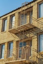 Brick building facade with brown fire escape ladders and platforms with large windows and blue sky background Royalty Free Stock Photo