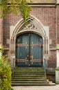 Brick building with two green doors featuring detailed and ornate designs Royalty Free Stock Photo