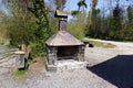 brick chemine oven with copper roof, metal grill without meat, the grill is not in use, day,sunshine, tree with ivy, gravel