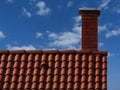 brick chimney and brown clay tile sloped roof ridge. blue sky with clouds Royalty Free Stock Photo