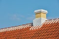 Brick chimney designed on slate roof of house building outside against blue sky background. Construction of exterior