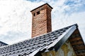 Brick chimney pipe on metal roof of house. Royalty Free Stock Photo