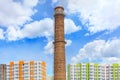 The brick chimney of the thermal power plant rises above the new houses under construction in the sleeping area of the city Royalty Free Stock Photo