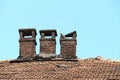 Brick chimney on tile roof of an old wooden house