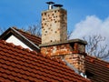 Red clay roof detail with brick chimneys under blue sky Royalty Free Stock Photo