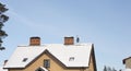 Brick chimneys heated the cottage against a blue sky, the snow-covered roof of the cottage Royalty Free Stock Photo