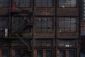 Brick exterior of an industrial building with banks of windows and fire escape Royalty Free Stock Photo