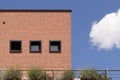 Brick facade with three windows, blue sky and a cloud, parma. Italy