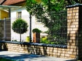 Brick fence post or pier. ceramic capping. wire mesh grille fence panels. lush green grass Royalty Free Stock Photo