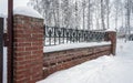 brick fence with wrought iron grating on top covered with snow Royalty Free Stock Photo