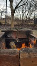 Brick fireplace with bright bonfire inside. Red flames in old burnt mangal. Grunge textures of countryside in cold weather.