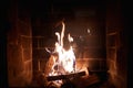 Brick fireplace with cozy wood fire burning, warm glow Royalty Free Stock Photo