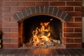 A brick fireplace in which a fire burns