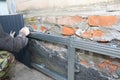 Brick House foundation wall repair, renovation with builder hands installing metal sheets for waterproofing and protect from