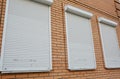 Brick house with metal roller shutters on the windows for protection Royalty Free Stock Photo