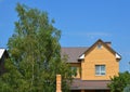 A brick house with a metal roof, fascia and box ends, roof gutters, a small attic window, and a window with metal security bars,