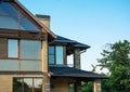 Brick house with panoramic windows, multilevel roof, glazed facade, chimney with forging, closeup.