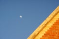 Brick house roof and growing moon in clear blue sky during the day Royalty Free Stock Photo