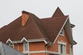 Brick house with white windows and brown tiled roof with chimneys