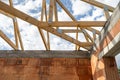 Brick house with wooden roof truss, support beams and ceilings under blue sky Royalty Free Stock Photo