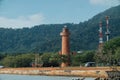 Brick lightho use on the shore, against the background of the jungle. Asia