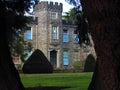 Brick manor house with topiary front yard enclosed by tree trunks. Royalty Free Stock Photo