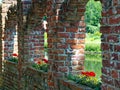 Brick masonry arches with flowers on window sills and view to pond and park Royalty Free Stock Photo