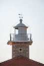 The brick and metal dome of the lighthouse with the directions of the world. White arrows in a clear sky designating north, south