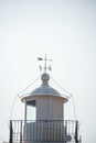 The brick and metal dome of the lighthouse with the directions of the world. White arrows in a clear sky designating north, south