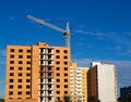 Brick multistory building under construction with crane on the site, blue sky background Royalty Free Stock Photo