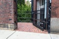 Brick passageway between buildings with partially open gate door