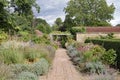A brick path runs between abundant flower beds in an English country garden
