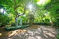 A brick paved garden with lush green trees and a white pergola