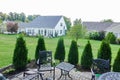 Brick paver backyard patio with bordering by arborvitae trees looking out into common grassy areas towards the back of other